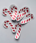 Stickers en forme de sucre d’orge de Noël à rayures rouges et blanches, disposés sur un fond gris clair.
Il reste à ajouter les dimensions et à préciser la vente à l’unité ou en lot dans la description.