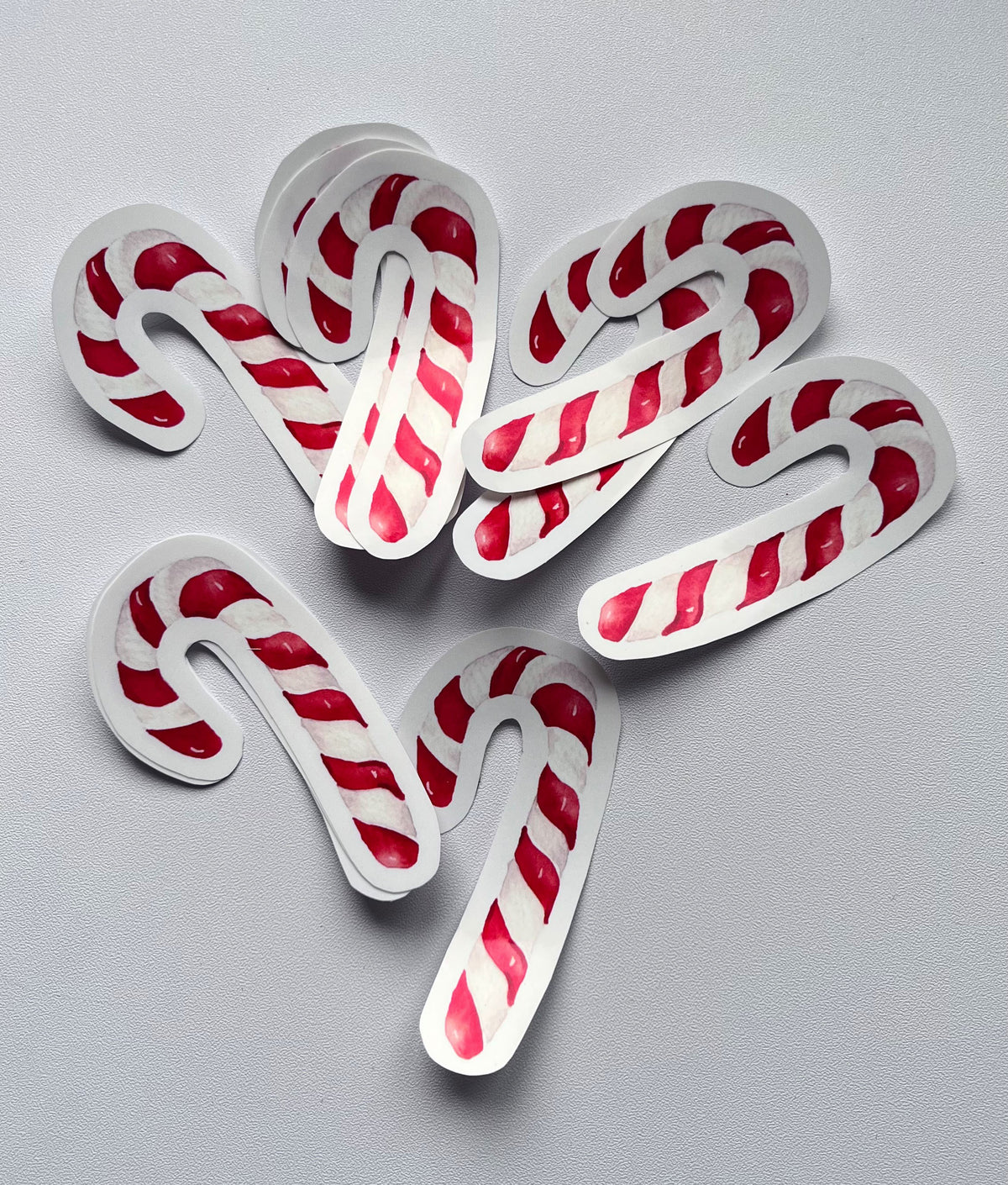 Stickers en forme de sucre d’orge de Noël à rayures rouges et blanches, disposés sur un fond gris clair.
Il reste à ajouter les dimensions et à préciser la vente à l’unité ou en lot dans la description.