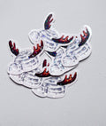 Stickers représentant un igloo gris avec une entrée arrondie et des bois de renne bruns, ornés d’étoiles holographiques, sur un fond gris clair.