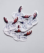 Stickers représentant un igloo gris avec une entrée arrondie et des bois de renne bruns, ornés d’étoiles holographiques, sur un fond gris clair.