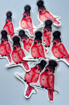Stickers d’oiseaux rouges et roses portant un bonnet noir à pompon, perchés sur des branches enneigées et disposés sur un fond gris clair.